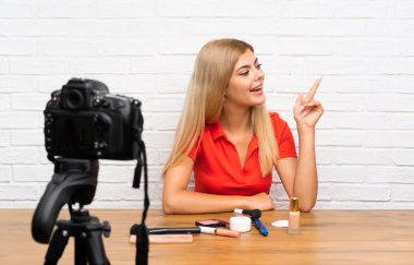 Genç blogger kız yan parmak işaret eden bir video öğretici kayıt