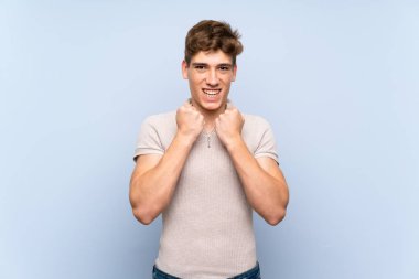Izole mavi duvar üzerinde Yakışıklı genç adam kötü bir durum tarafından sinirli