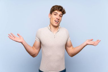 Şok yüz ifadesi ile izole mavi duvar üzerinde Yakışıklı genç adam