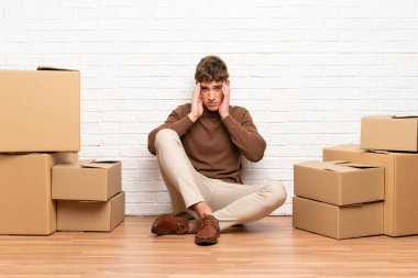 Yakışıklı genç adam kutular arasında yeni bir evde mutsuz ve bir şey ile sinirli hareket. Negatif yüz ifadesi