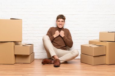 Yakışıklı genç adam bir zafer kutluyor kutuları arasında yeni bir evde hareket