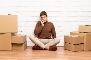 Kutular arasında yeni bir evde hareket eden yakışıklı genç adam sinirli ve korkmuş