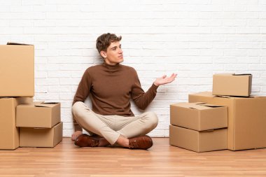 Yakışıklı genç adam avuç içinde hayali copyspace tutan kutular arasında yeni evde hareket