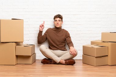 Yakışıklı genç adam işaret parmağı ile geri işaret kutuları arasında yeni bir evde hareket