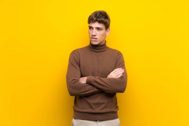 Karışık yüz ifadesi ile izole sarı arka plan üzerinde Yakışıklı genç adam