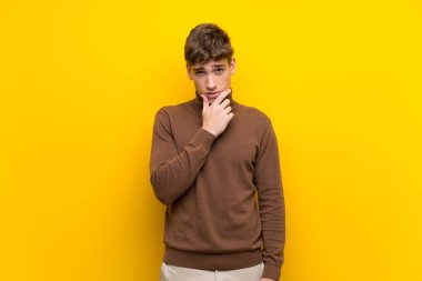 Izole sarı arka plan düşünme üzerinde Yakışıklı genç adam