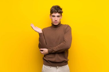 Izole sarı arka plan üzerinde Yakışıklı genç adam bir şey anlamak için mutsuz