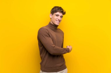 Izole sarı arka plan üzerinde yakışıklı genç adam geri işaret