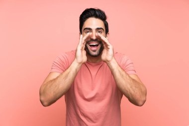 Ağzı tamamen açık bağırarak izole pembe arka plan üzerinde Yakışıklı genç adam