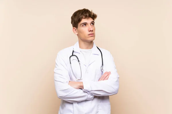 笑顔で見上げる孤立した壁の上のハンサムな医者の若者 — ストック写真