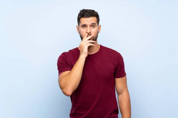 Hombre Guapo Sobre Fondo Azul Aislado Sorprendido Sorprendido Mientras Mira —  Fotos de Stock