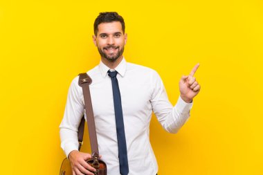 Izole sarı arka plan üzerinde Yakışıklı işadamı şaşırttı ve yan parmak işaret