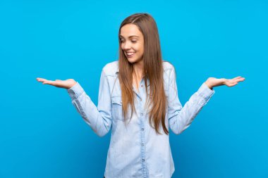 İki eliyle copyspace tutan izole mavi arka plan üzerinde genç kadın