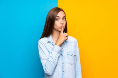 Renkli arka plan üzerinde genç kadın sessizlik jest yapıyor
