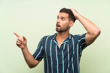 Izole arka plan üzerinde Yakışıklı adam şaşırttı ve yan parmak işaret