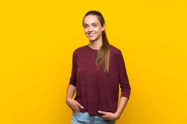 Sarı arka planda yaşayan genç bir kadın gülüyor.