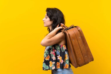 Bir vintage evrak çantası tutan izole sarı arka plan üzerinde genç kadın