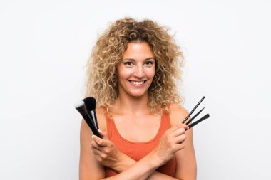 Makyaj fırçası ile kıvırcık saçlı genç sarışın kadın