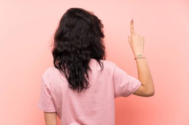 İzole pembe arka plan üzerinde genç kadın işaret parmağı ile geri işaret