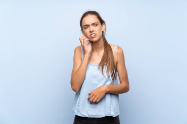 Diş ağrısı ile izole mavi arka plan üzerinde genç kadın
