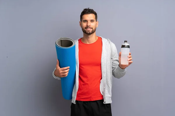 Giovane uomo sportivo con stuoia e con una bottiglia d'acqua — Foto Stock