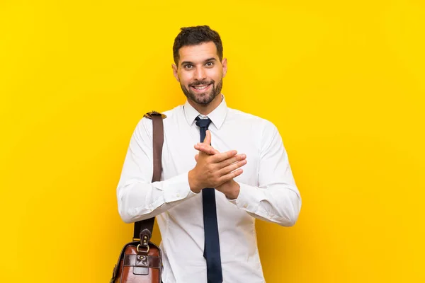 Handsome businessman over isolated yellow background applauding