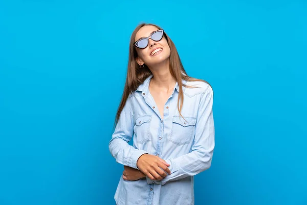 Jonge Vrouw Geïsoleerde Blauwe Achtergrond Met Een Bril Glimlachend — Stockfoto