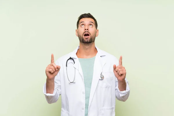 Jonge Doctor Man Geïsoleerde Groene Muur Wijzend Met Wijsvinger Een — Stockfoto