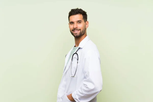 Młody Lekarz Człowiek Przez Izolowany Zielony Ściana — Zdjęcie stockowe