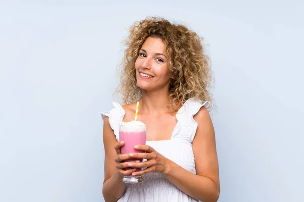 Молодая блондинка с вьющимися волосами держит клубничный молочный коктейль — стоковое фото