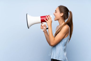 Izole mavi arka plan üzerinde genç kadın bir megafon ile bağırıyor