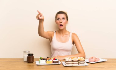 Bir masada farklı mini kek çok uzakta işaret eden genç kadın