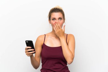 Sürpriz yüz ifadesi ile cep telefonu kullanan genç sarışın kadın