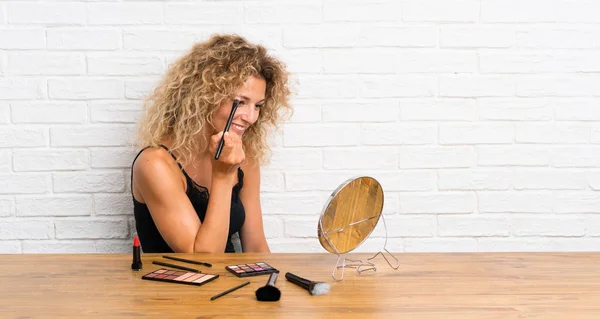 Jeune femme avec beaucoup de brosse de maquillage dans une table — Photo