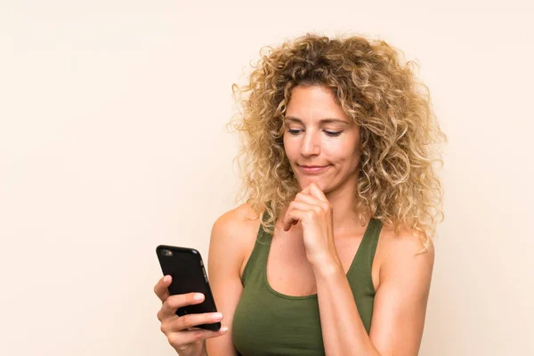 Young blonde woman with curly hair using mobile phone — Stock Photo, Image