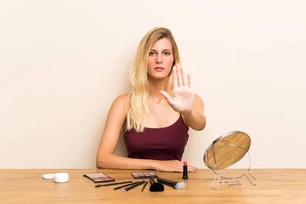 Jeune Femme Blonde Avec Cosmétique Dans Une Table Faisant Geste — Photo