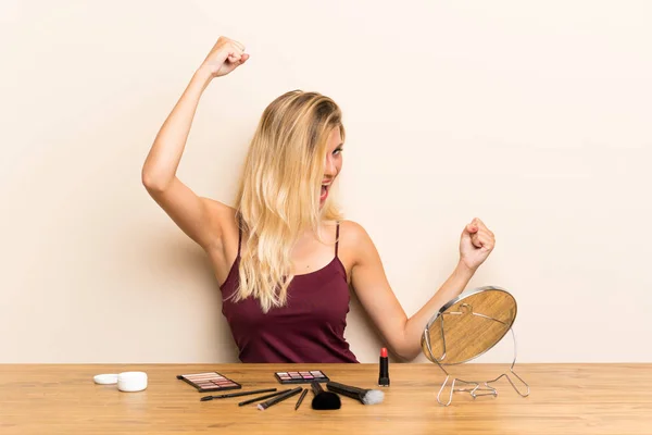 Joven Rubia Con Cosmética Una Mesa Celebrando Una Victoria — Foto de Stock