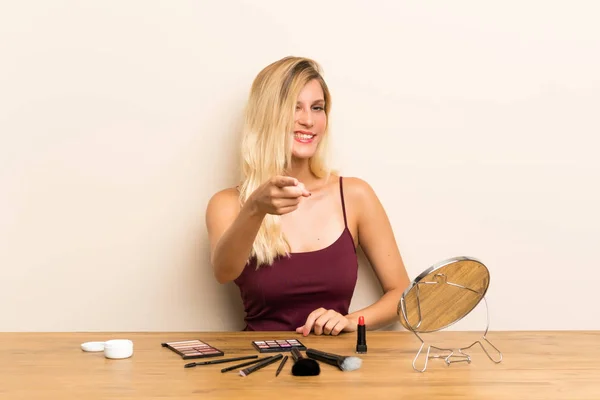 Junge Blonde Frau Mit Kosmetik Einem Tisch Zeigt Mit Dem — Stockfoto