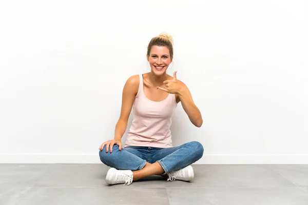 Mujer Rubia Joven Sentada Suelo Haciendo Gesto Telefónico — Foto de Stock