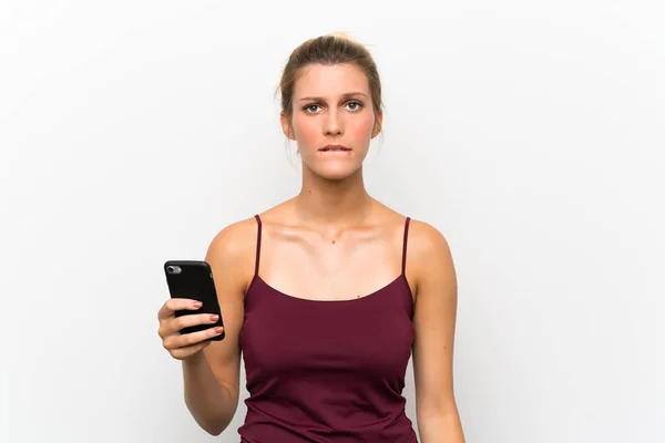 疑いを持ち 顔の表情を混乱させる携帯電話を使用して若いブロンドの女性 — ストック写真