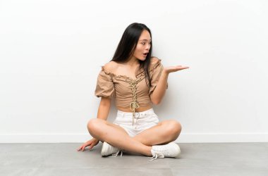 Genç asyalı kız avuç üzerinde copyspace hayali tutarak katta oturan