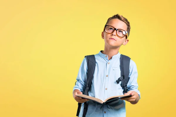 Criança Estudante Com Mochila Óculos Segurando Livro Fundo Amarelo — Fotografia de Stock