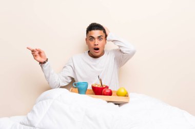 Yatakta kahvaltı eden genç adam şaşırttı ve parmağını yana doğru işaret etti