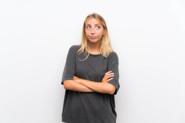 Sarışın genç kadın omuzları kaldırırken şüphe jest yapma izole beyaz arka plan üzerinde