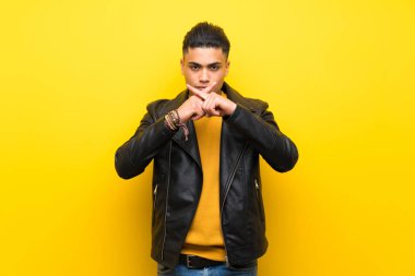 İzole sarı arka plan üzerinde sessizlik jest bir işaret gösteren genç adam