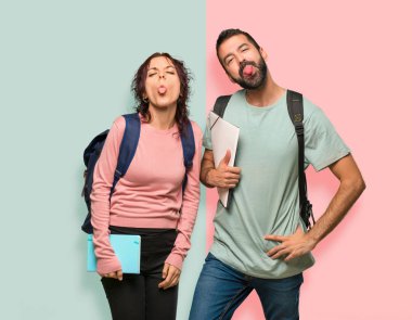 Renkli duvarda komik bir görünüme sahip kamera da dil gösteren sırt çantaları ve kitapları ile iki öğrenci