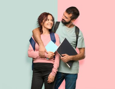 Renkli duvarda sırt çantaları ve kitaplar ile Mutlu iki öğrenci