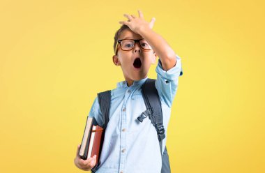 Sırt çantası ve gözlük ile öğrenci çocuk sarı arka plan üzerinde çözüm gerçekleştirmek niyetinde