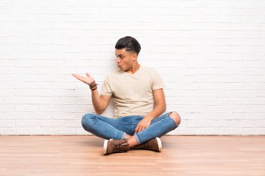 Genç adam avuç üzerinde hayali copyspace tutarak katta oturan