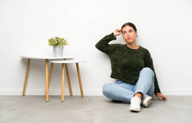 Genç kadın şüpheler ve karışık yüz ifadesi ile katta oturan